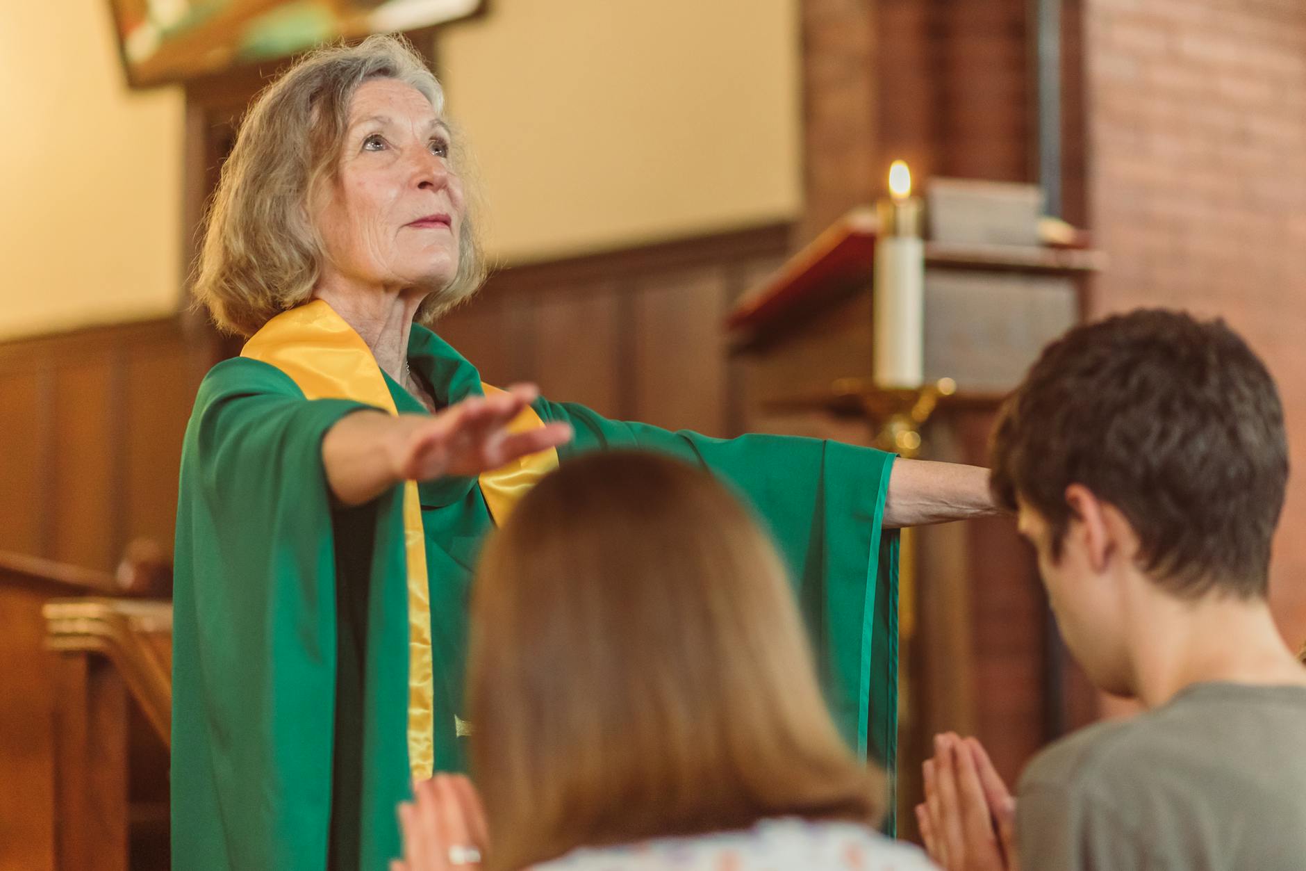 Starsza pastorka w zielonej szacie prowadzi modlitwę w kościele