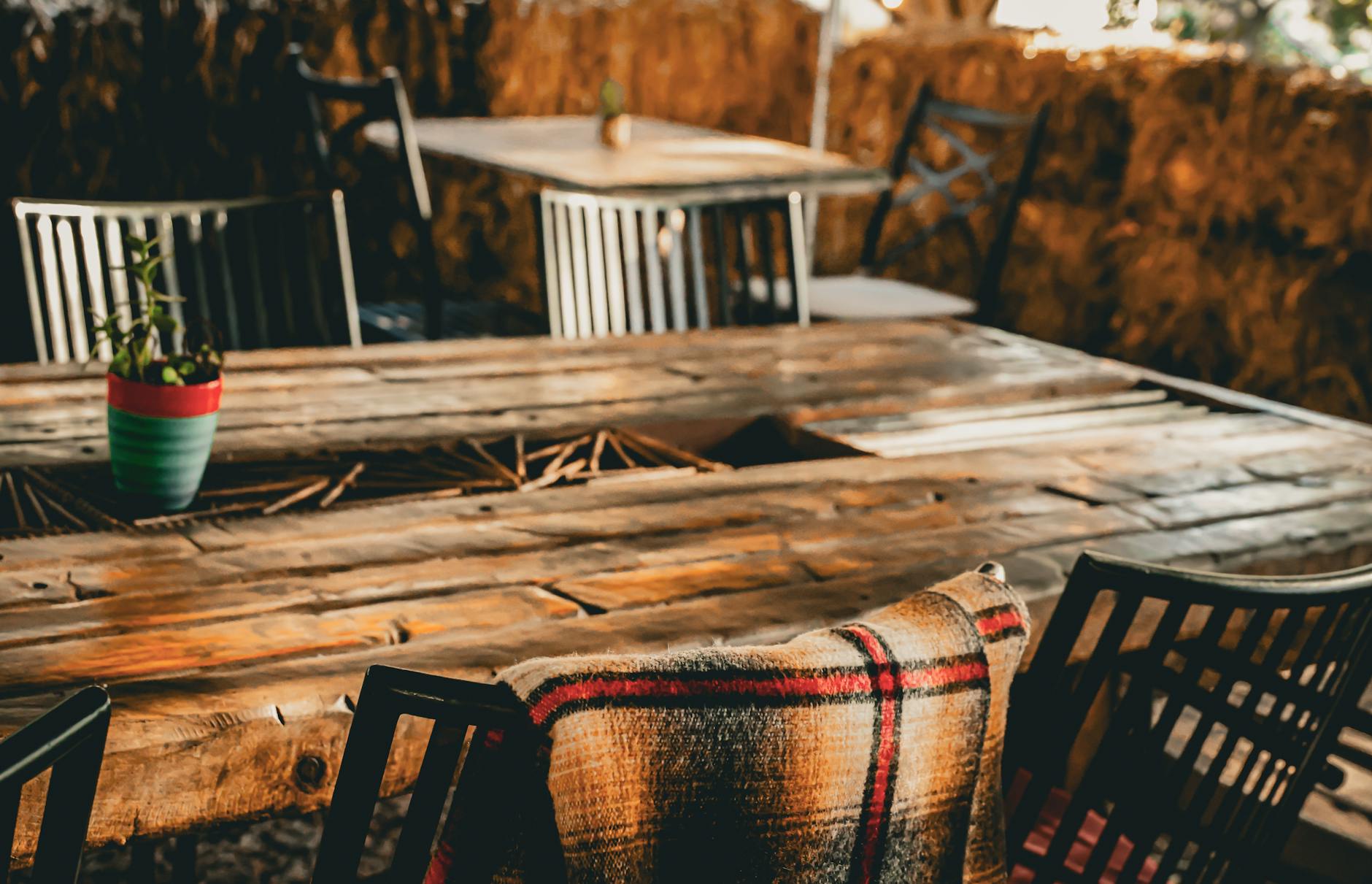 Jedzenie w Sztutowie po sezonie: które miejsca działają jesienią i zimą? Rustyczny ogródek restauracyjny z kocem i rośliną na drewnianym stole