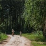 Mama z dzieckiem jadą na rowerze leśną ścieżką w słoneczny dzień