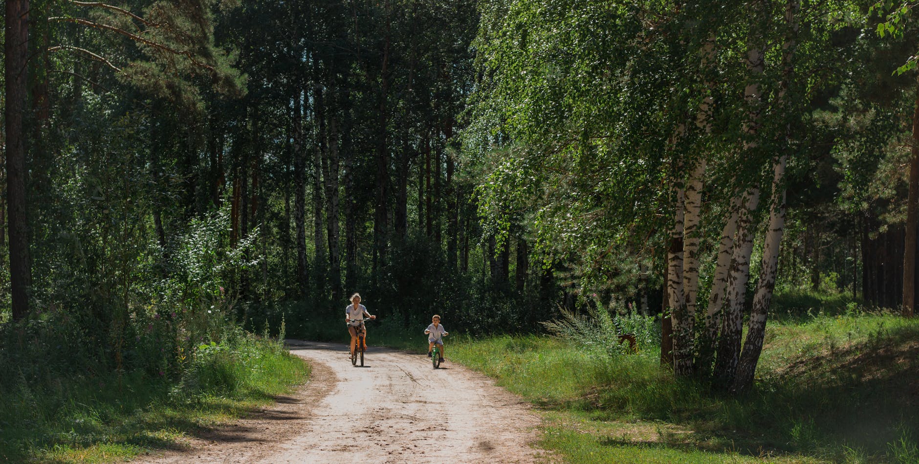 Rowerem z dzieckiem w gminie Sztutowo: nowe mapy, objazdy i bezpieczne odcinki Mama z dzieckiem jadą na rowerze leśną ścieżką w słoneczny dzień
