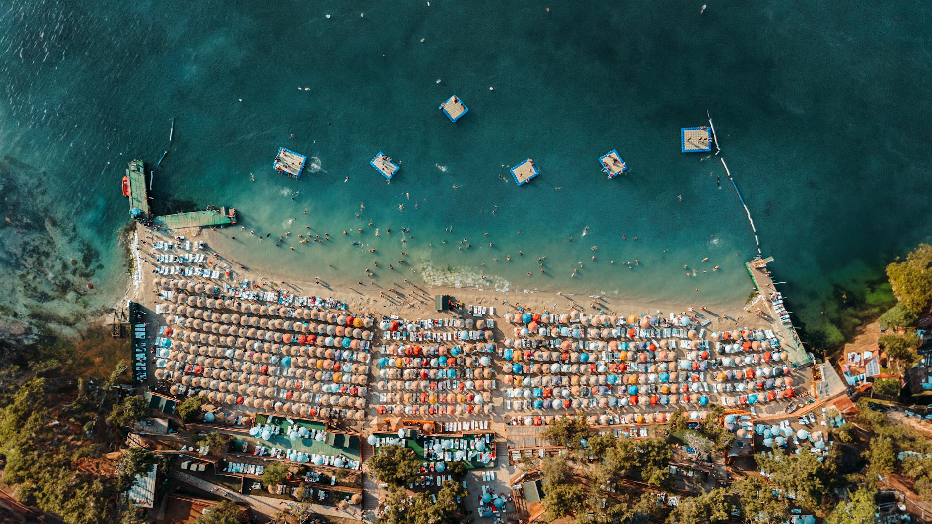 Plaża z lotu ptaka z kolorowymi parasolami i turkusową wodą