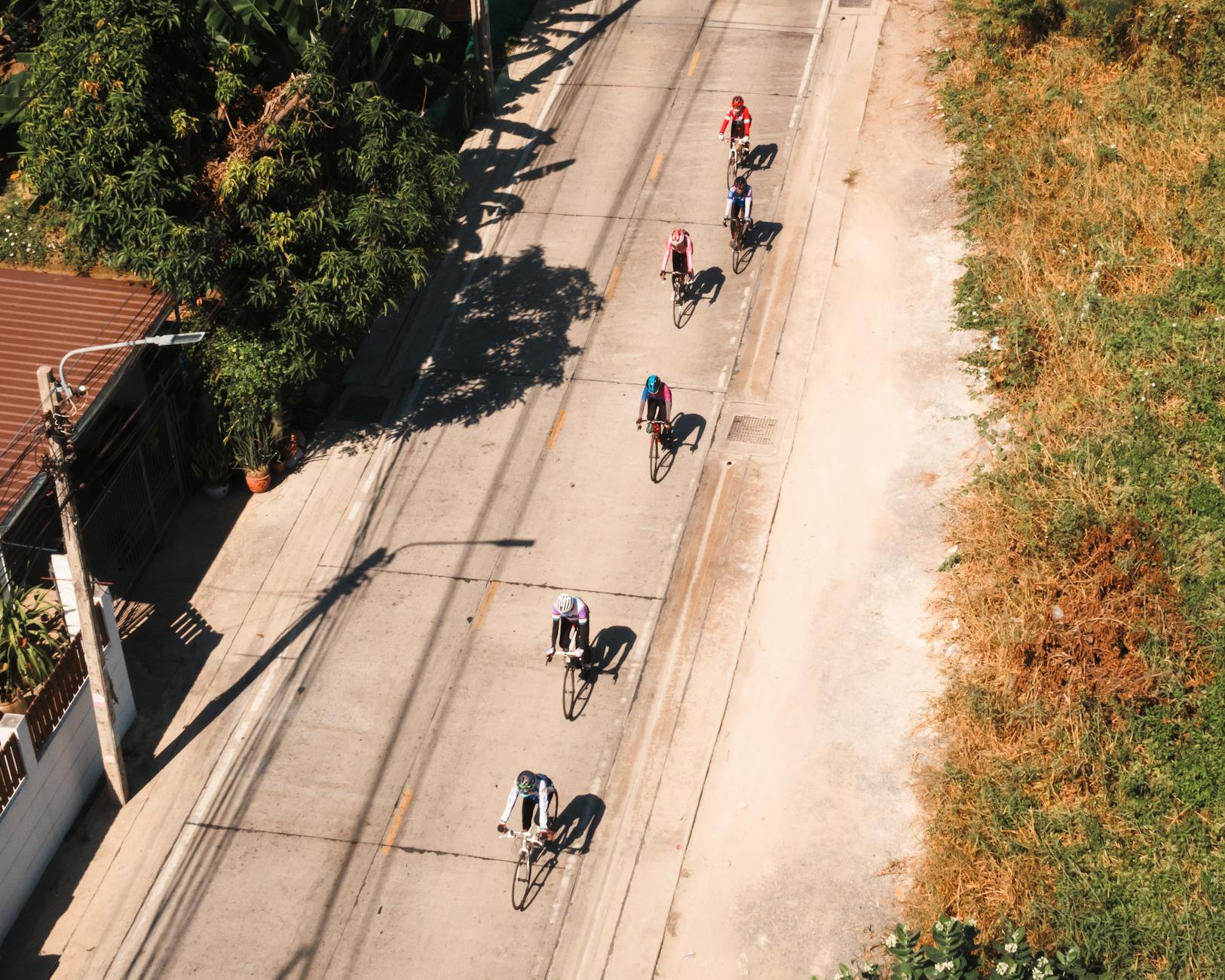 Rowerzyści jadą słoneczną ulicą z lotu ptaka