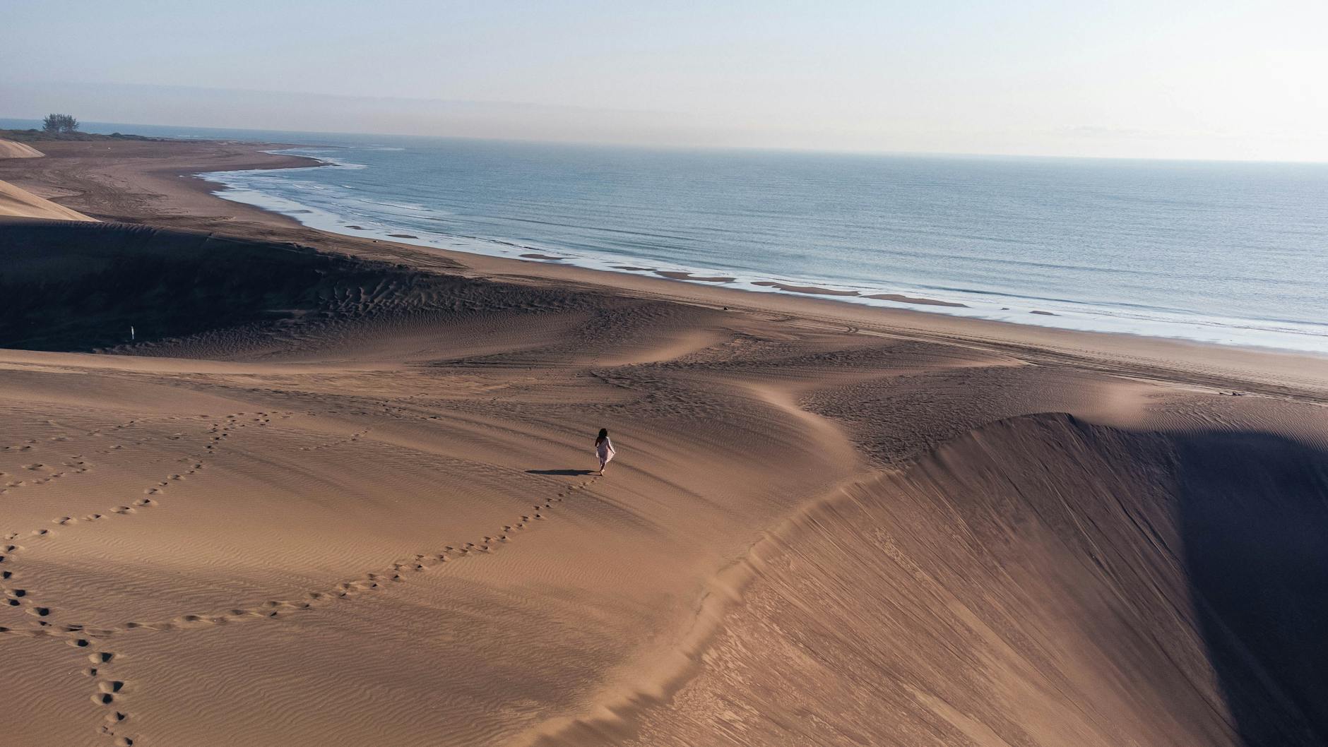 Spacerowicz idzie samotnie po rozległych wydmach nad morzem