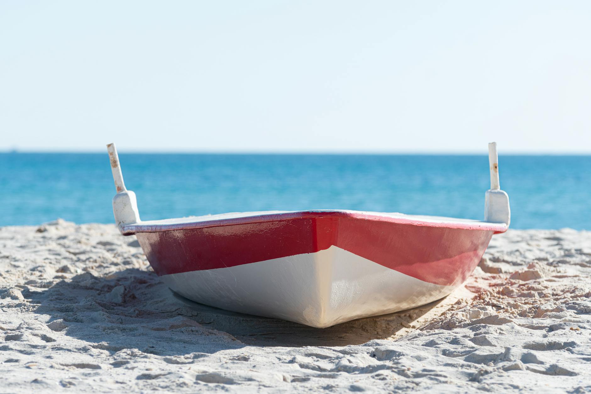 Czerwono-biała łódź na piaszczystej plaży w Hammamecie nad turkusowym morzem