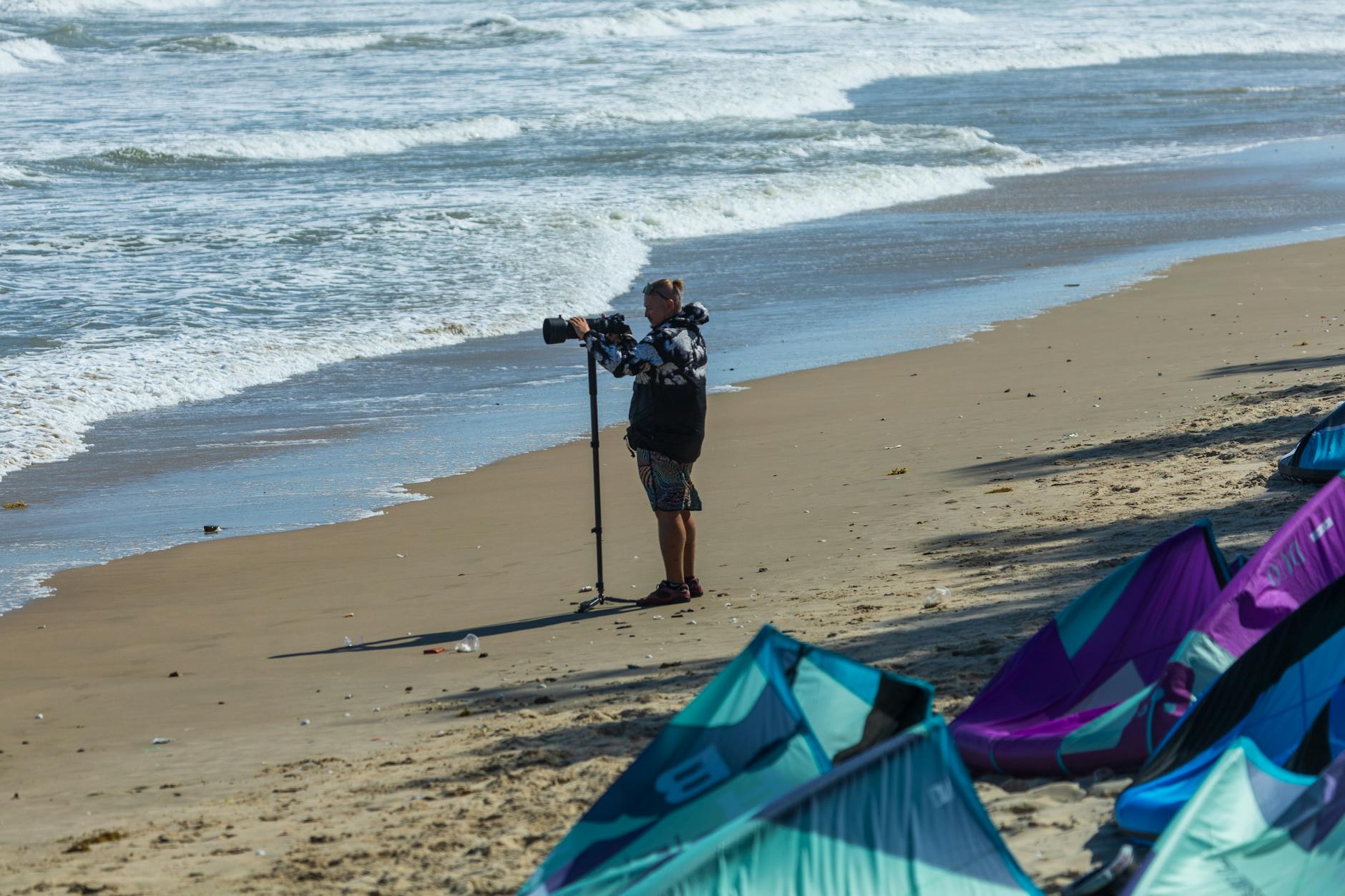 Sztutowo dla fotografów: kadry z wydm, lasu i plaży Fotografujący mężczyzna na plaży w Sztutowie z latawcami i falami