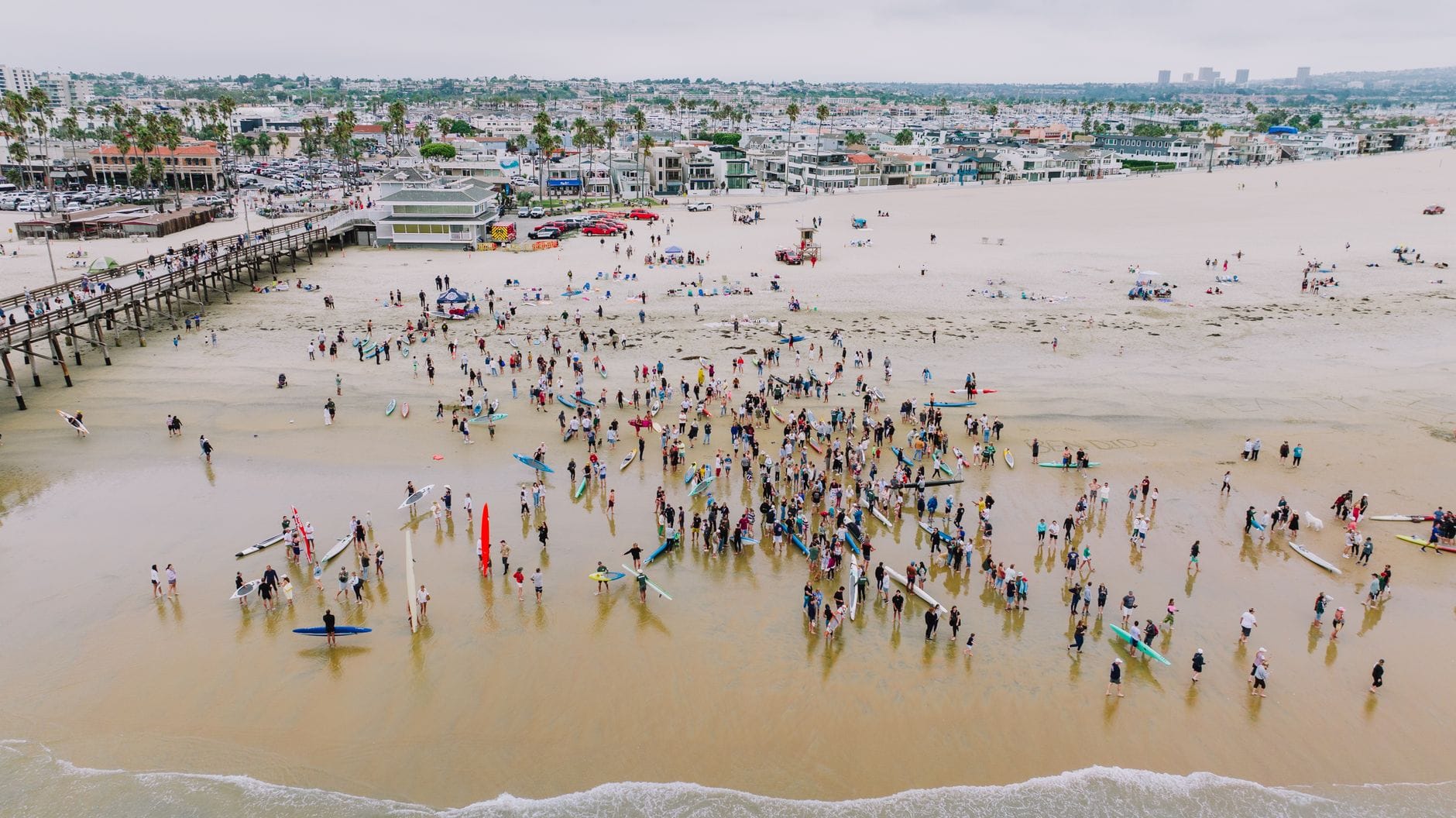 Surferzy z deskami na słonecznej plaży, widok z lotu ptaka