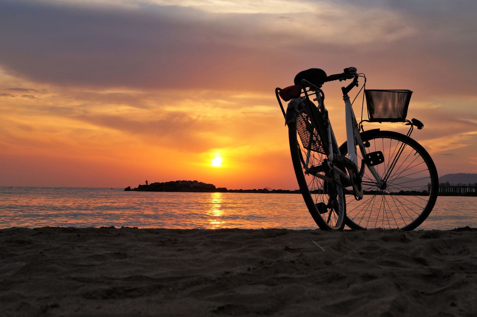Sylwetka roweru na piaszczystej plaży w blasku zachodu słońca