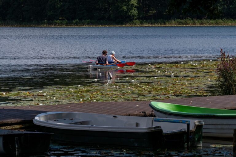 Para w czerwonym kajaku wśród lilii wodnych na spokojnym jeziorze